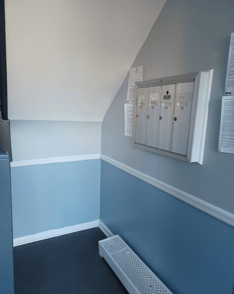 Silver mailboxes mounted on a two-tone blue wall above a white decorative radiator cover.