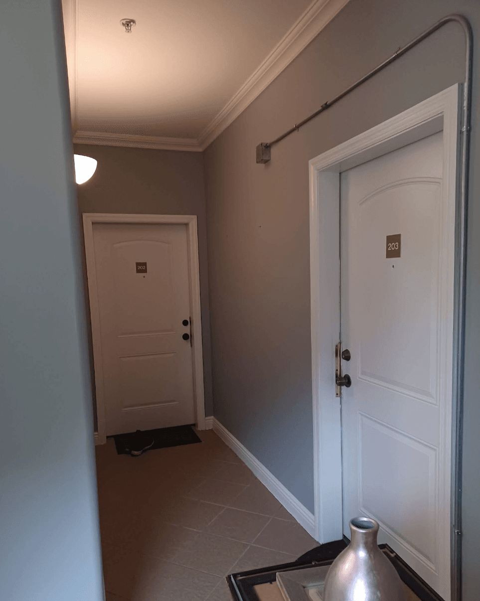 Grey hallway featuring two white doors numbered 202 and 203 and tiled flooring.